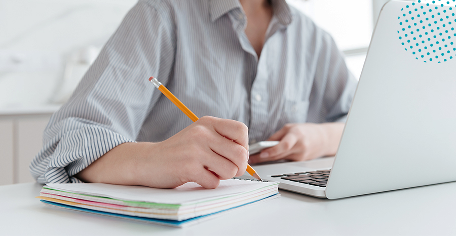 imagem de um homem olhando para um computador eanotando em um caderno ao lado