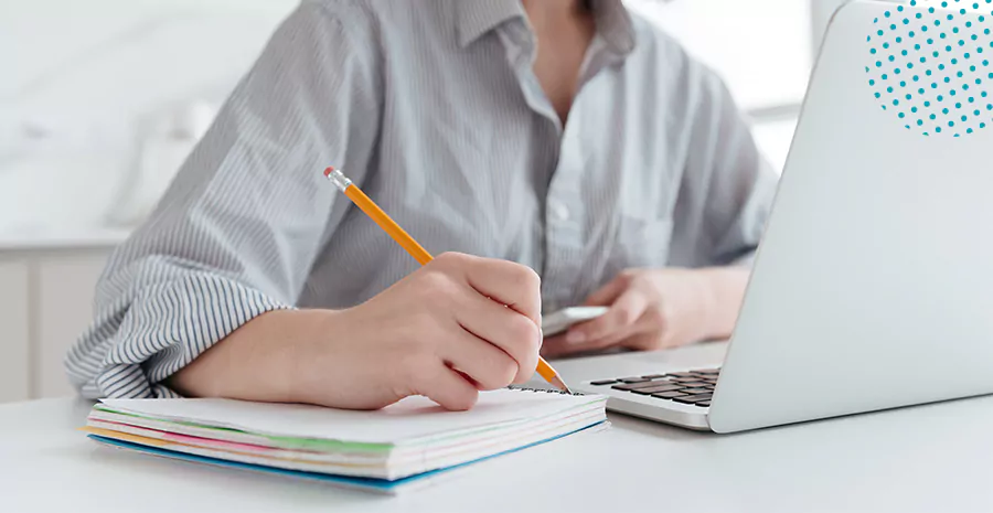 imagem de um homem olhando para um computador eanotando em um caderno ao lado