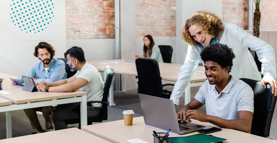 imagem de um grupo de profissionais sentados em três mesas olhando para computadores e conversando