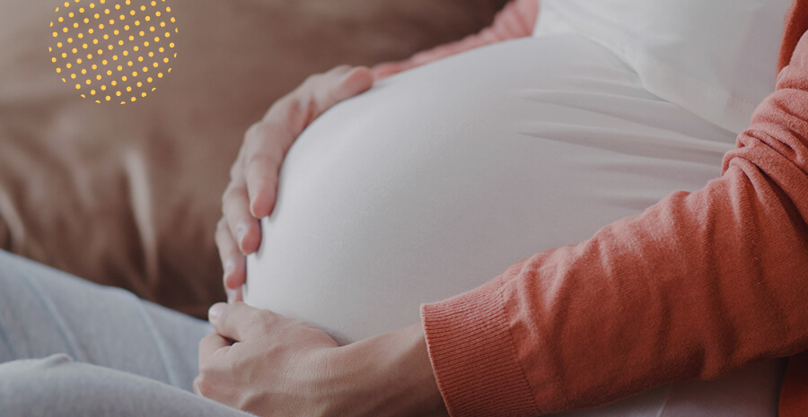 imagem de uma mulher grávida sentada com a mão apoiada na barriga