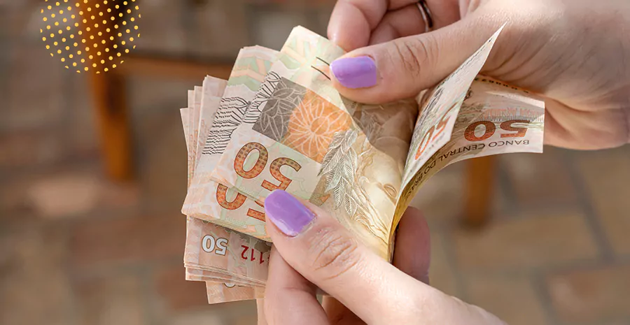 imagem de uma pessoa segurando notas de cinquenta reais