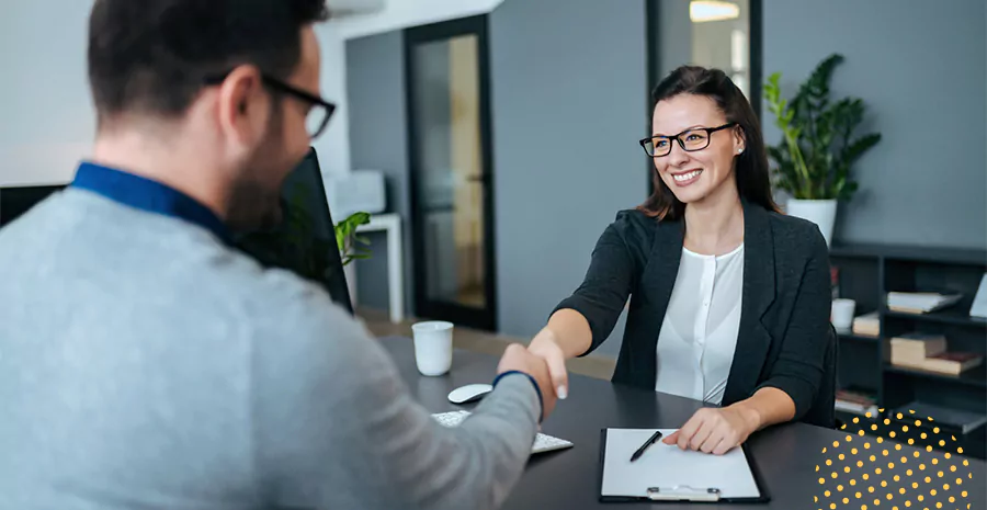 imagem de um homem e uma mulher sentados em uma mesa sorrindo e apertando as mãos