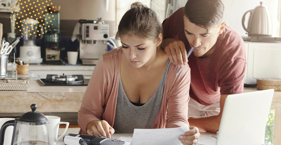 imagem de um homem e uma mulher usando uma calculadora e segurando um papel