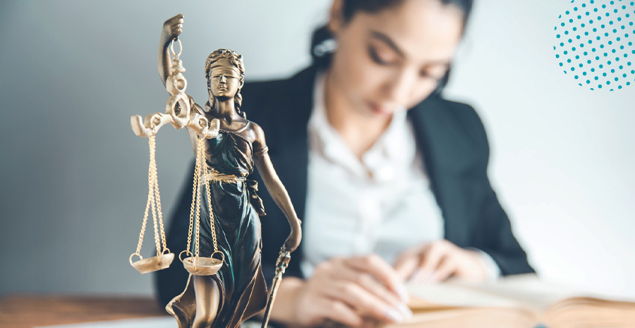 imagem de uma mulher sentada lendo um livro com uma escultura de direito em cima da mesa