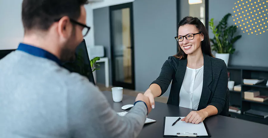 imagem de um homem e uma mulher sentados em uma mesa se cumprimentando