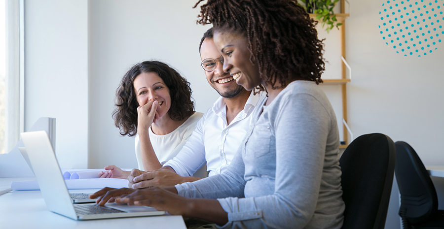 imagem de duas mulheres e um homem sentados em uma mesa olhando para um computador