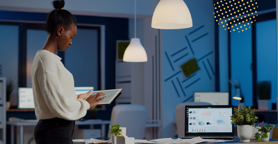 imagem de uma mulher em pé na frente de um computador segurando um tablet
