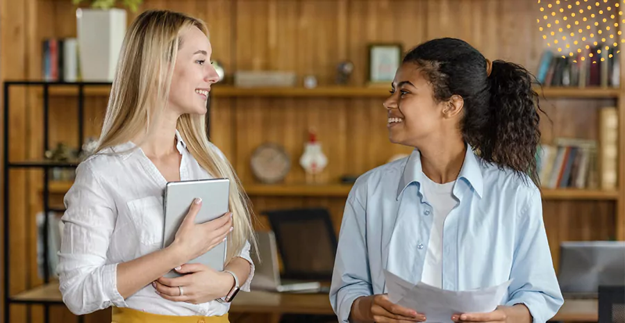 imagem de duas mulheres em pé sorrindo e se olhando