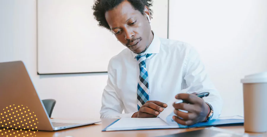 imagem de um homem sentado mexendo em um caderno e usando fones de ouvido