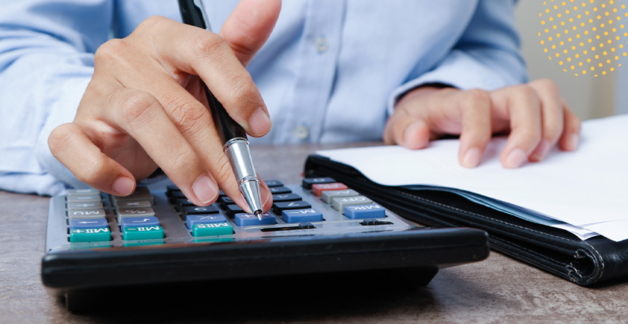 imagem de um homem digitando em uma calculadora e segurando uma caneta