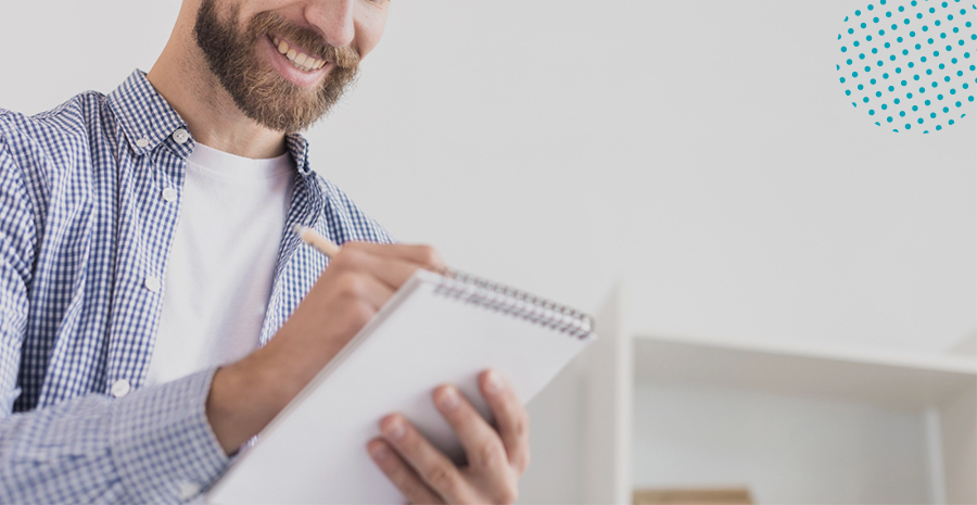 imagem de um homem sorrindo anotando em um caderno