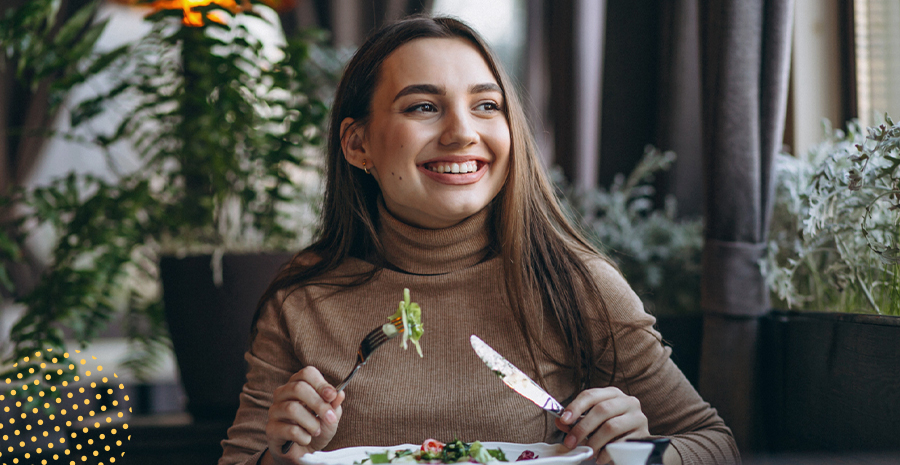 imagem de uma mulher sorrindo sentada comendo salada