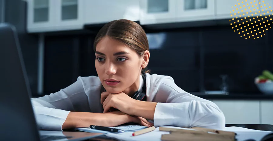 imagem de uma mulher sentada na frente de um computador apoiando os braços na mesa