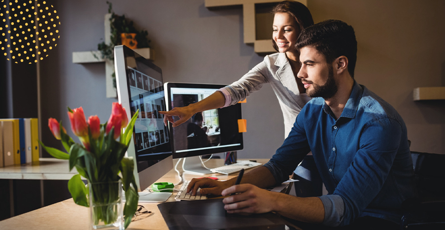 imagem de uma mulher e um homem olhando para um computador em cima de uma mesa