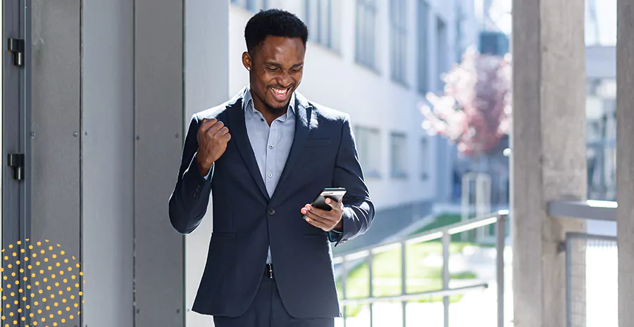 imagem de um homem sorrindo e celebrando segurando um celular
