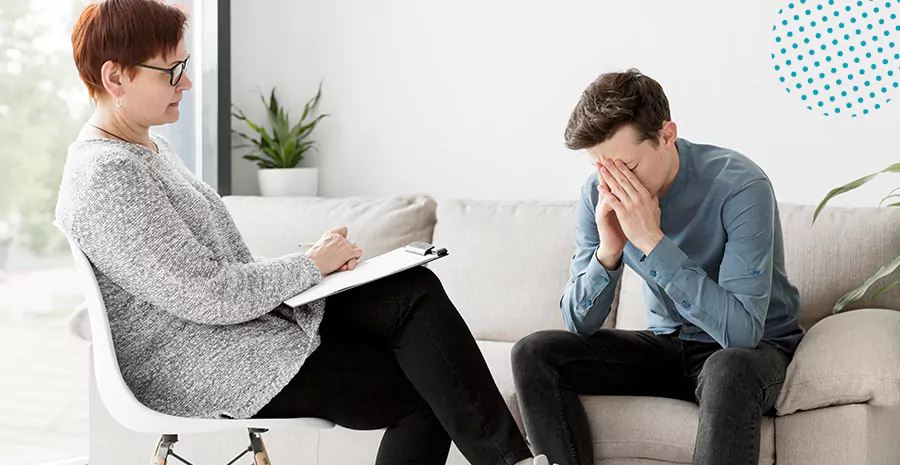 imagem de uma mulher sentada em uma cadeira escrevendo em um caderno e um homem sentado em um sofá com as mãos no rosto preocupado