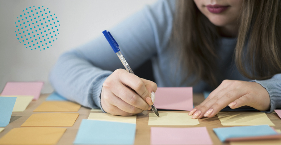 imagem de uma mulher sentada escrevendo em um postit