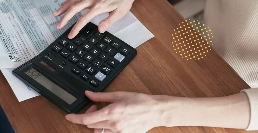 imagem de uma pessoa usando uma calculadora com folhas espalhadas ao lado