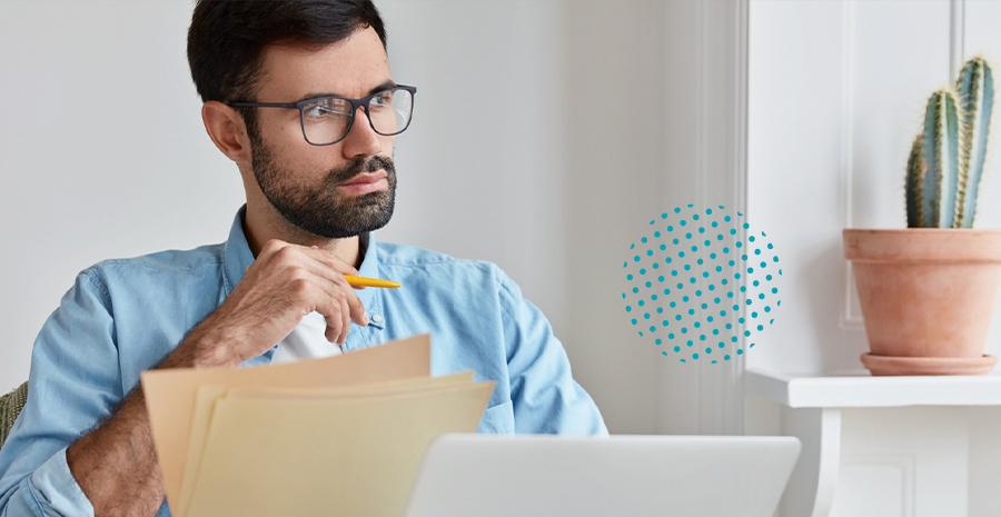 imagem de um homem sentado na frente de um computador segurando um lápis