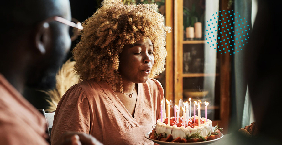 imagem de uma mulher assoprando velas em um bolo de aniversário