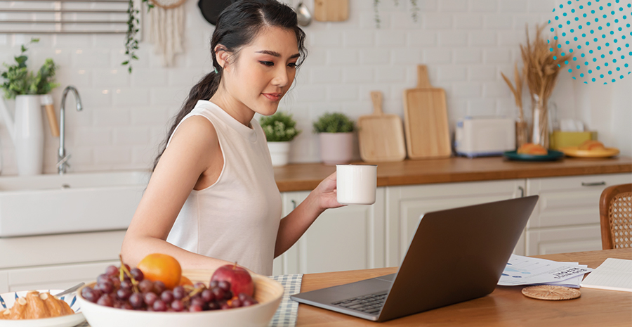 imagem de uma mulher segurando uma xícara e olhando para um computador