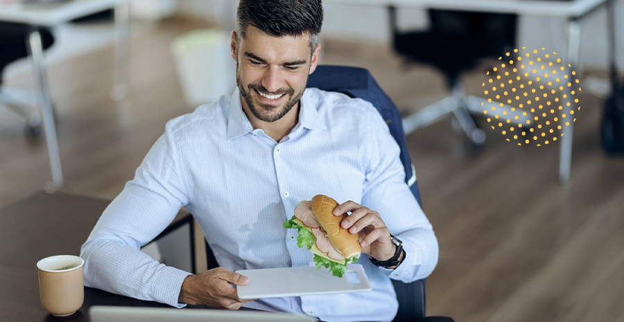 imagem de um homem sorrindo sentado segurando um sanduíche