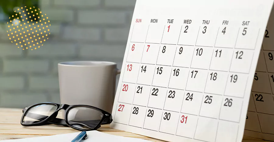 imagem de um calendário um óculos e uma xícara em cima de uma mesa