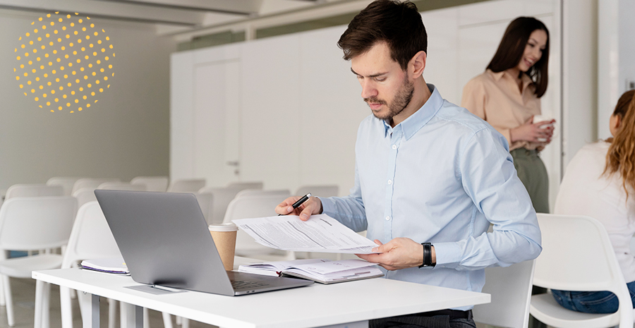 imagem de um homem sentado na frente de um computador segurando uma folha