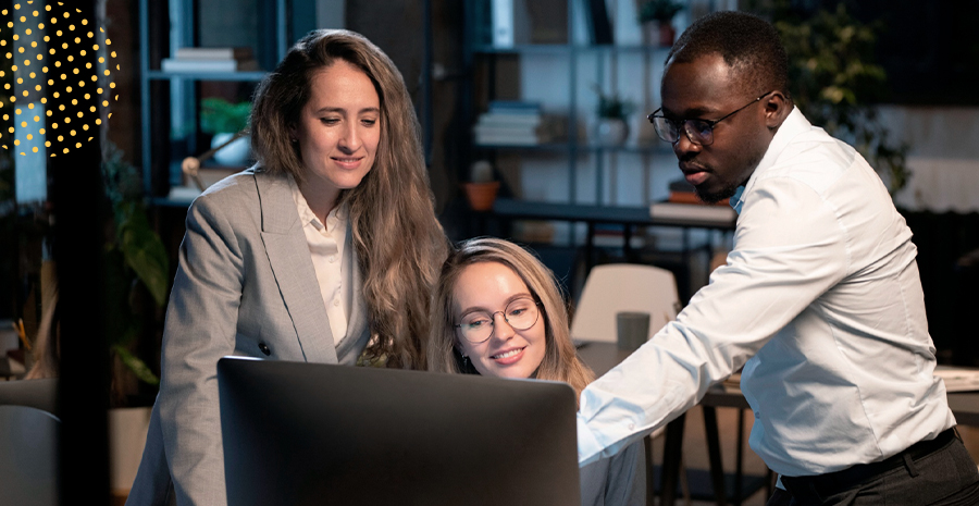 imagem de duas mulheres e um homem olhando para um computador