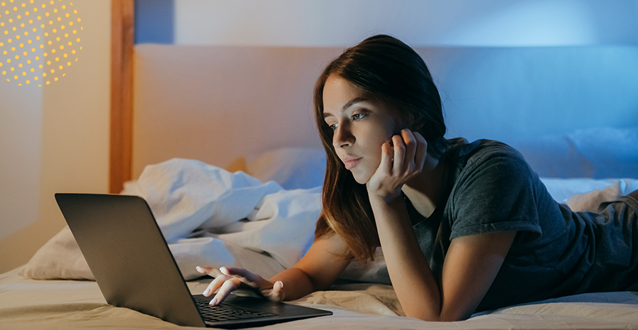 imagem de uma mulher deitada mexendo em um computador
