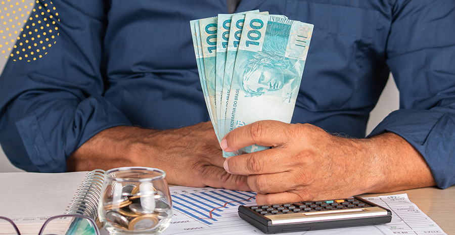 imagem de um homem sentado segurando notas de cem reais