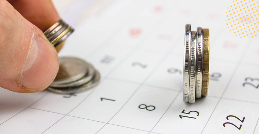 Moedas sendo tocadas por uma mão em cima de uma calendário