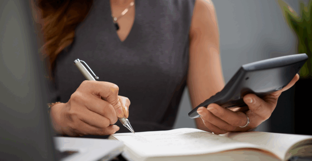 Mulher usando calculadora e escrevendo em caderno, estratégia para negócios online, educação ou organização pessoal.
