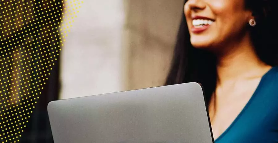 Mulher sorrindo segurando notebook, imagem representa convenção coletiva