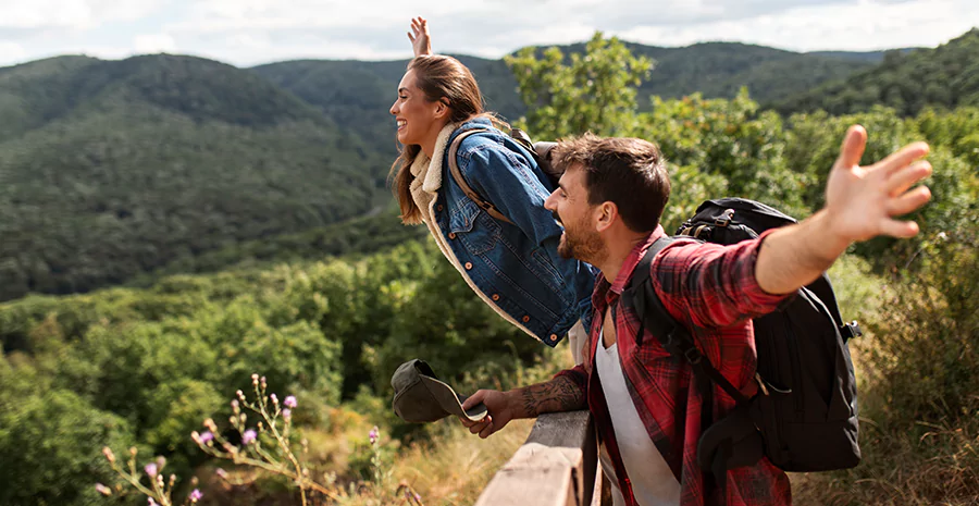 homem e mulher de braços abertos sorrindo na natureza, representando o período sabático